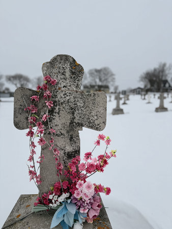 Wreaths and flowers on a gravestone at a cemetery in winter, Quebec, Canada.
