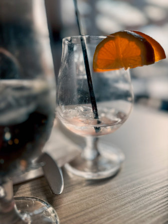 Cocktail in an empty glass with a straw on a wooden table in a bar