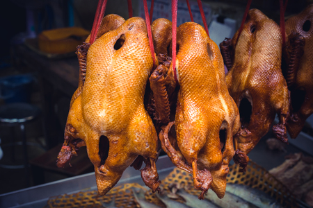 Lot of chicken bodies are hanging on the red ropes in a street market in Bangkok , Thailandの写真素材