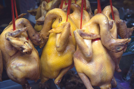 Lot of chicken bodies are hanging on the red ropes in a street market in Bangkok , Thailandの写真素材