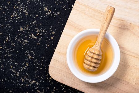 Wooden honey dipper with fresh honey in white plateの写真素材