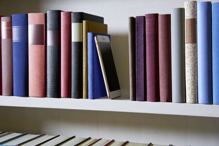 Mobile phone in bookshelfの写真素材