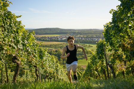 Good looking teenager sprinting up vineyards.の写真素材