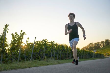 Young man in white shorts and tanktop dancing next to vineyardsの写真素材