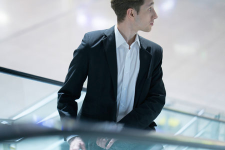 Close up of a young handsome businessman on a staircase in an office building wearing a suitの写真素材