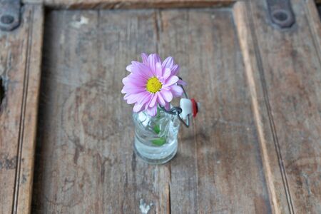 Small glass bottle with flowers on wooden shabby furniture from aboveの写真素材