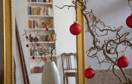 Close up of a branch with christmas balls, reflections in a mirror with golden frame, loft apartmentの写真素材