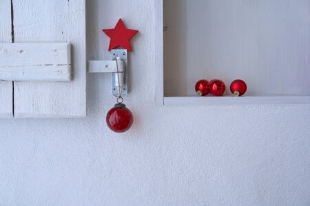 Close up of a white shelf with a white shabby wooden shutter nicely decorated with red christmas decoration, copy spaceの写真素材