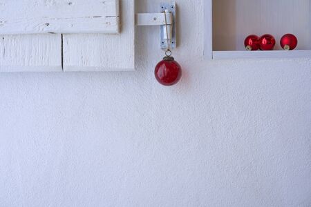 Close up of a white shelf with a white shabby wooden shutter nicely decorated with red christmas decoration, copy spaceの写真素材