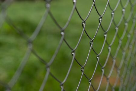 View through a fence, unsharp greenery in the backgroundの写真素材