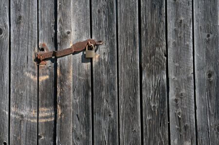Close up of a utility shed door with a rusty padlock and weathered planksの写真素材