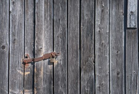 Close up of a utility shed door with a rusty padlock and weathered planksの写真素材