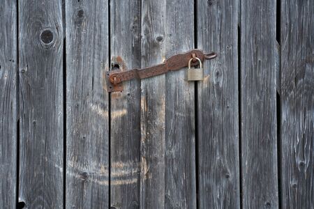 Detail of weathered planks of a shelter with a rusty padlockの写真素材