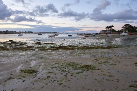 Romantic small harbour at low tide, peaceful dusk mood, little boats in the sand and shallow water, small city in the backgroundの写真素材