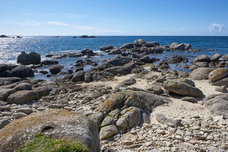Coast in Brittany with big rocks, moss and blue water, beautiful reflections on the sea, sunny dayの写真素材