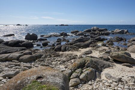 Coast in Brittany with big rocks, moss and blue water, light reflections on the seaの写真素材