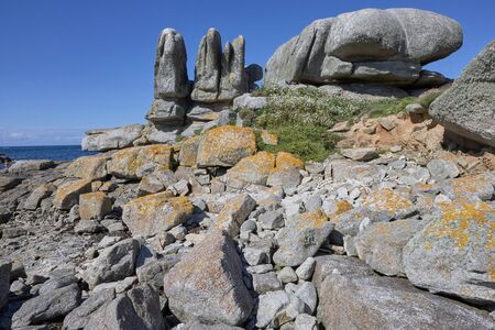 Big rocks with grass and moss at the coast of Brittany, blue skyの写真素材