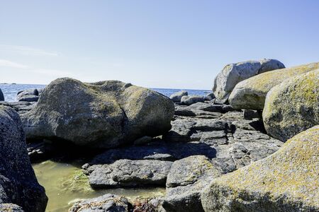Big rocks with grass and moss at the coast of Brittany, blue skyの写真素材