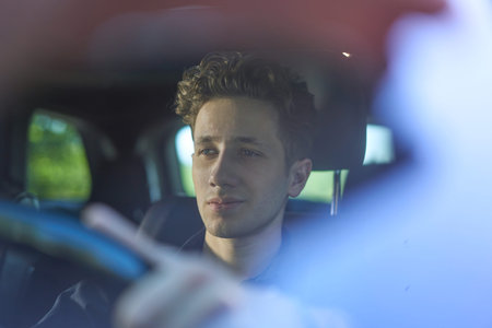 Young handsome smiling driver with hands on wheel.