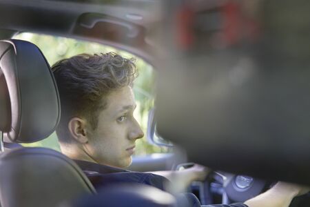 Portrait of a young and concentrated driver from behind, sideview of face.の写真素材