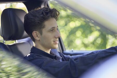 Young friendly driver sitting in a black seat in his carの写真素材
