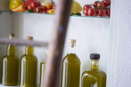 atmospheric detail closeup from a shelf in wall in country house rural style summer in spain.bottles oil vegetable paprika pepper lemon tomatos,blurred diffuse ladder in foregroundの写真素材