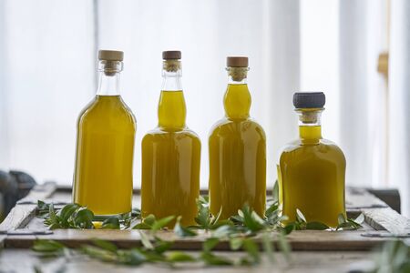 Four glass bottles of fresh organic olive oil or cooking oil in an old kitchen in Greeceの写真素材