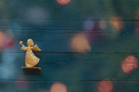 Christmas card with a golden angel in front of a colourful background with christmas lights