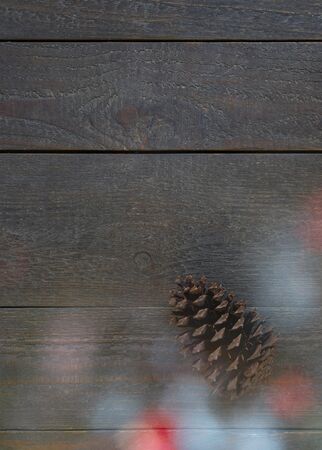 Christmas card with a fir cone and beautiful christmas lights in front of a wooden backgroundの写真素材