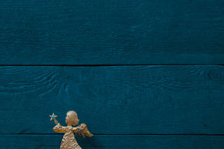 Golden angel in front of colourful blue-green background of textured wooden planks, copy spaceの写真素材
