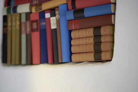 Close up of large assortment of german literature in white wall book shelf colourful hardcover booksの写真素材