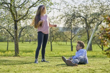 Young couple on a meadow between apple trees in spring laughing happily at each other and having funの写真素材