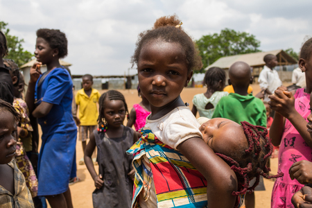 A little girl taking care of a baby and living in the wooden makeshift place of Internally Displaced Persons in Abuja, the Federal Capital of Nigeria.のeditorial素材