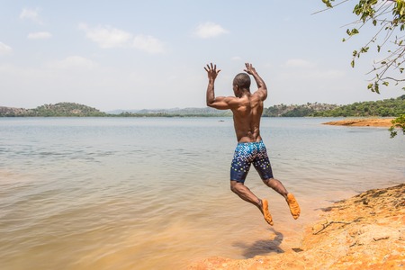 A young muscular athletic man takes a leap dive into the river in the morning.の写真素材