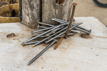 A pile of rusty nails on wooden board.の写真素材