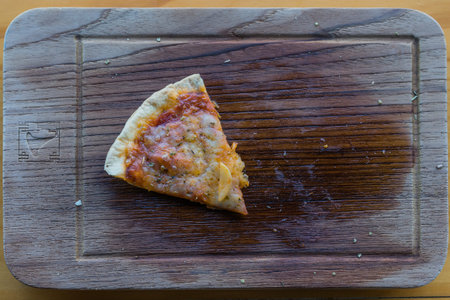 One piece of pizza on wood board
