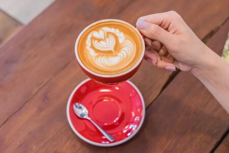 Red Coffee cup with heart shape latte art on wood table at caféの写真素材