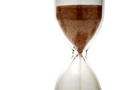 Time is money concept shot. Close view of sand flowing through an hourglass. Dramatic light, shallow DOF.の写真素材