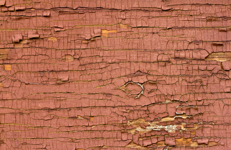 Old red oil paint peeling away from wood surface.