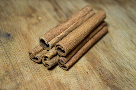 Five cinnamon sticks lie on an oak plankの写真素材