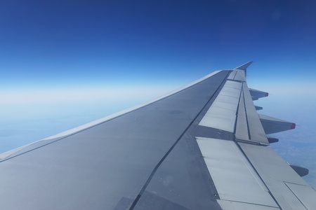 Wing of a flying aricraft with blue skyの写真素材