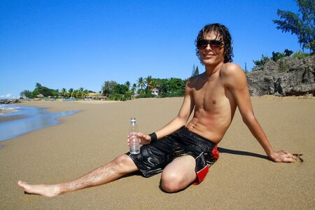 Man with bottle of water on beachの写真素材