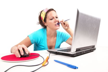 Woman with pen in teeth, looking to laptopの写真素材