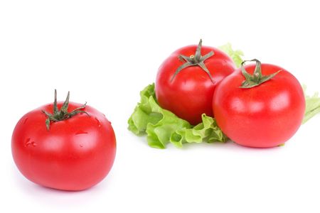 Tomatoes and green salad leafs on white, closed-upの写真素材