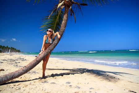 Girl in sunglasses relaxing near a palm, taking suntan の写真素材