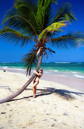 Girl in bikini near palm on caribbean beach の写真素材