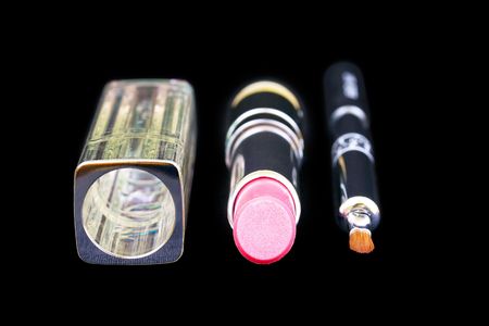Lip brush and pink lipstick with pack isolated on black の写真素材