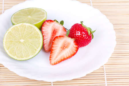 Strawberries and lime on white plate, closed-upの写真素材