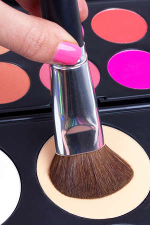 Professional make-up brush in hand on corector palette, closeupの写真素材