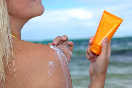 Tan woman applying sun protection lotionの写真素材